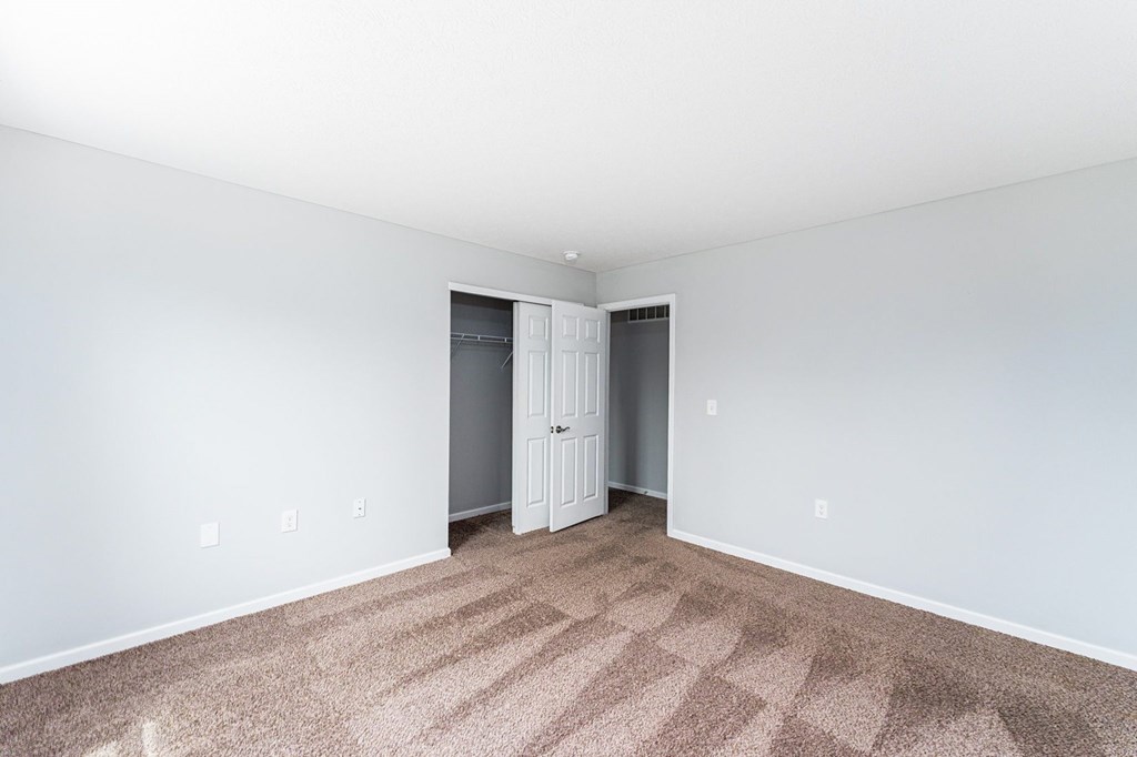 A room with a carpeted floor and a white door.