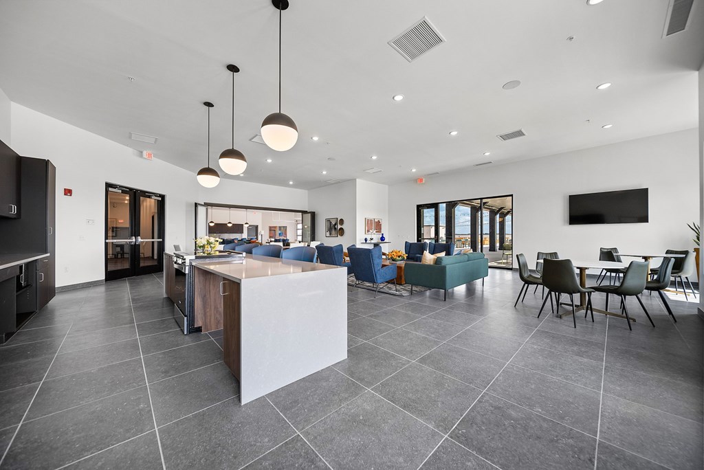 A modern kitchen with a large island and a dining area with chairs.