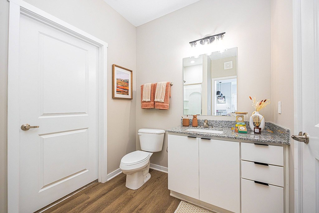 A white bathroom with a toilet, sink, and mirror.