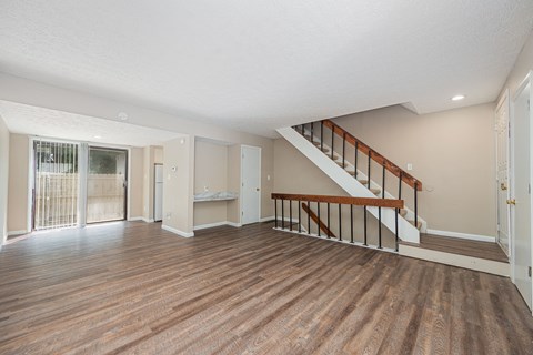 the living room and entryway of a house with a hard wood floor and stairs