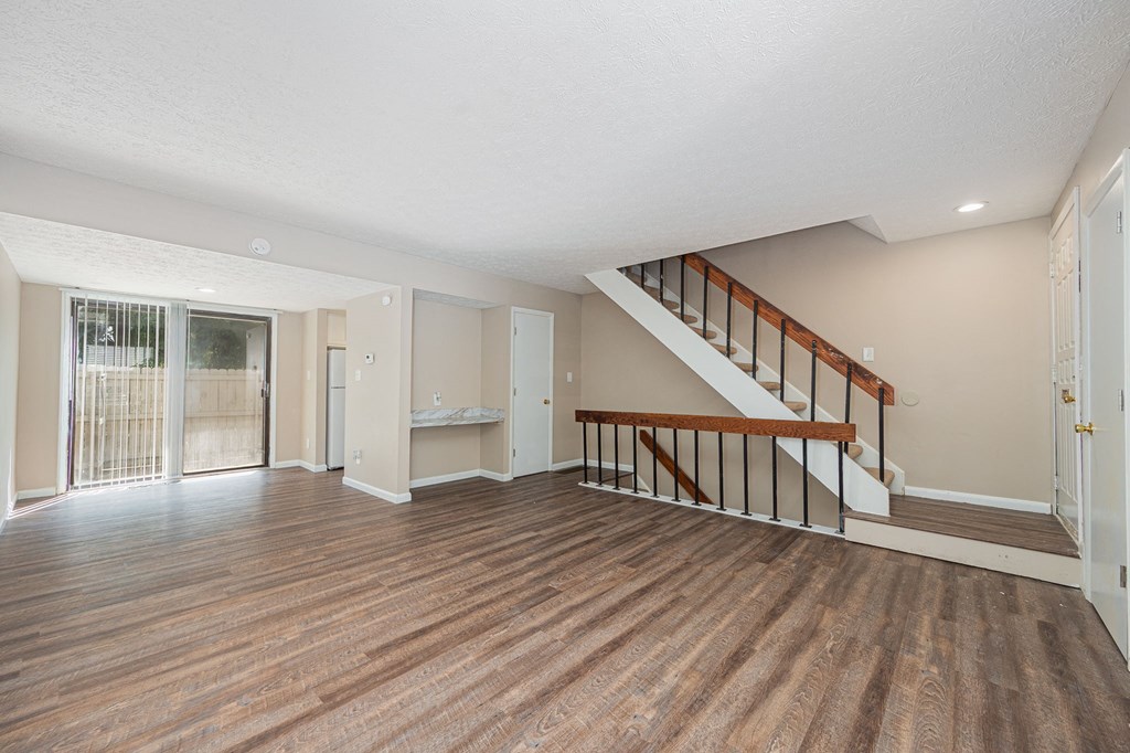 the living room and entryway of a house with a hard wood floor and stairs
