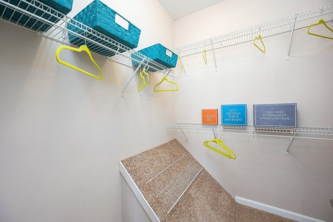 an empty closet with baskets and hooks on the wall