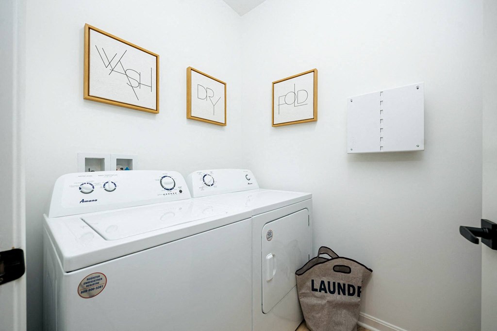 a washer and dryer in a laundry room with three pictures on the wall
