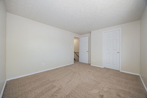A room with carpeted floor and two doors.