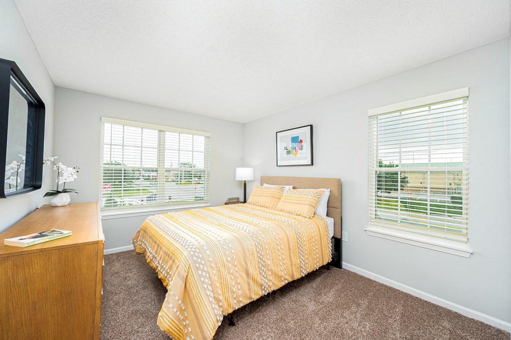 a bedroom with a yellow bed and two windows