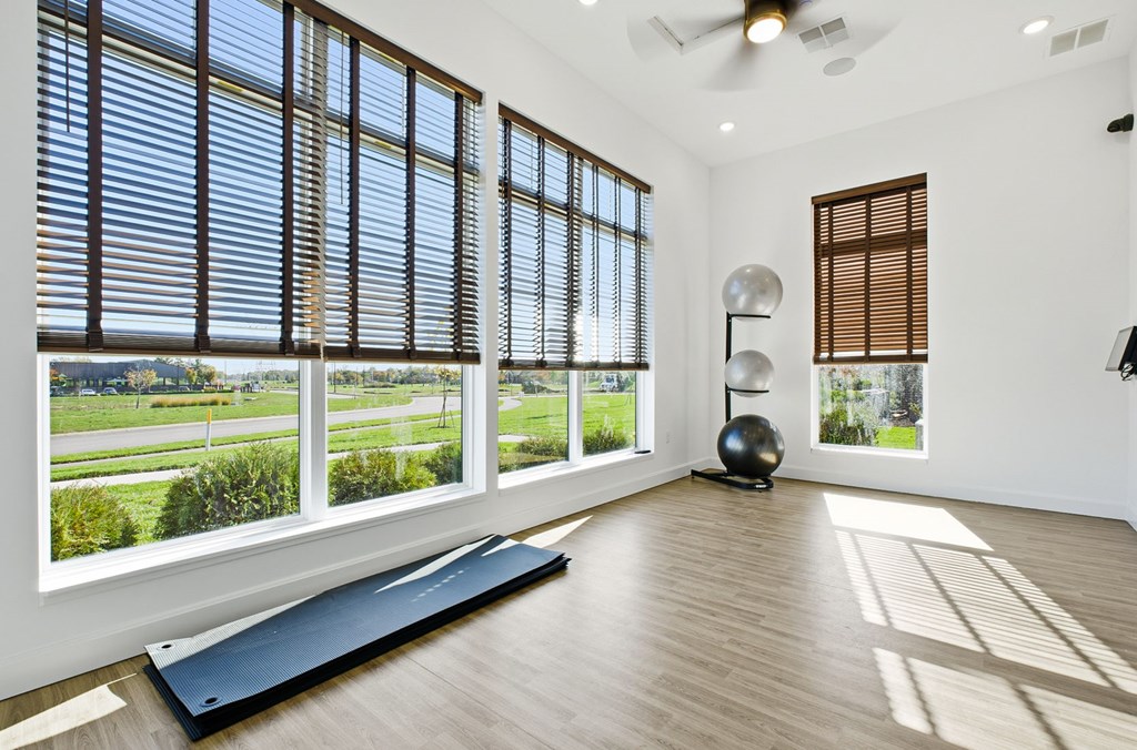A room with a large window and a yoga mat on the floor.