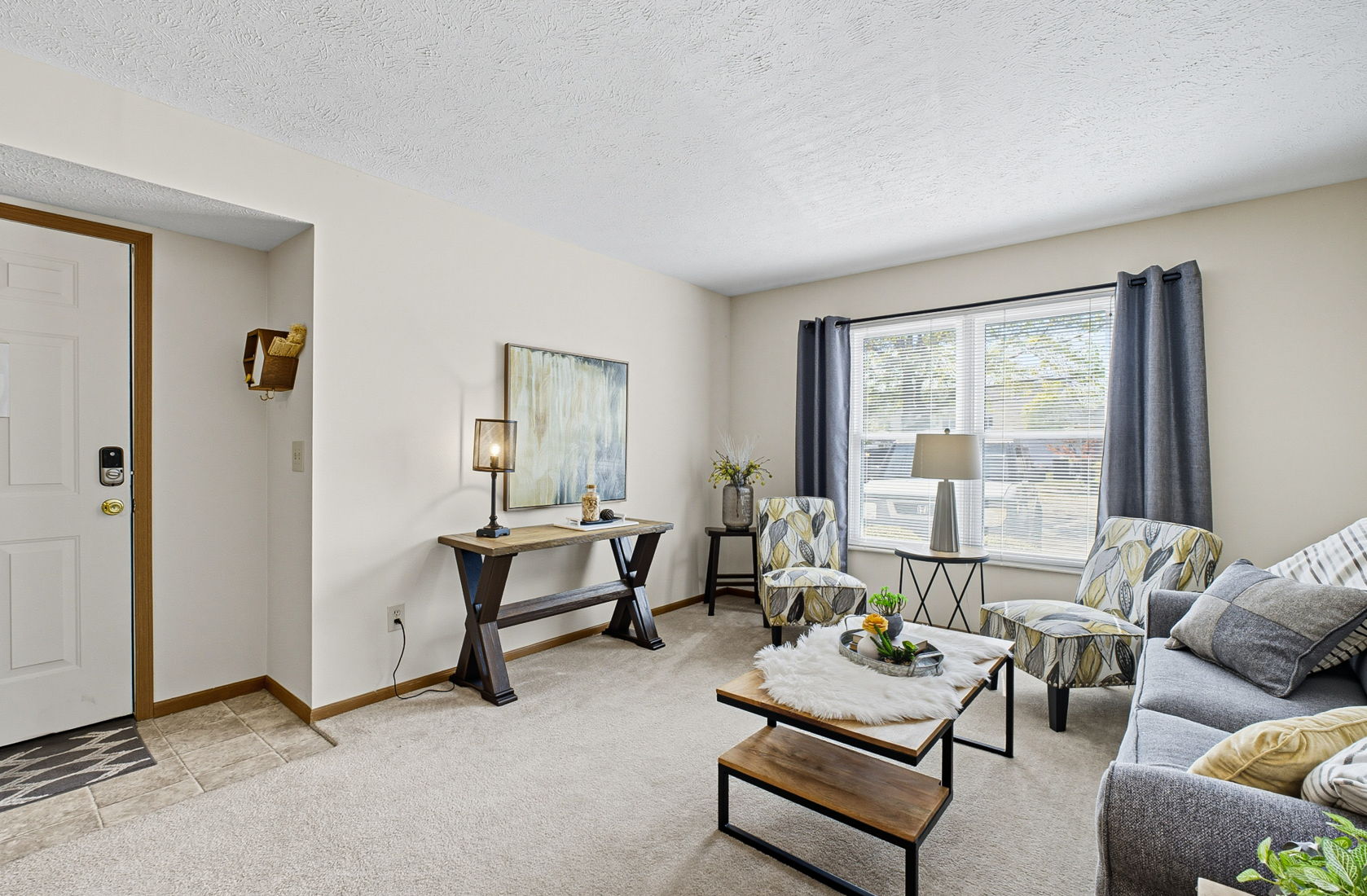 A living room with a grey couch, a coffee table, and a painting on the wall.