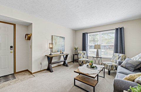 A living room with a grey couch, a coffee table, and a painting on the wall.
