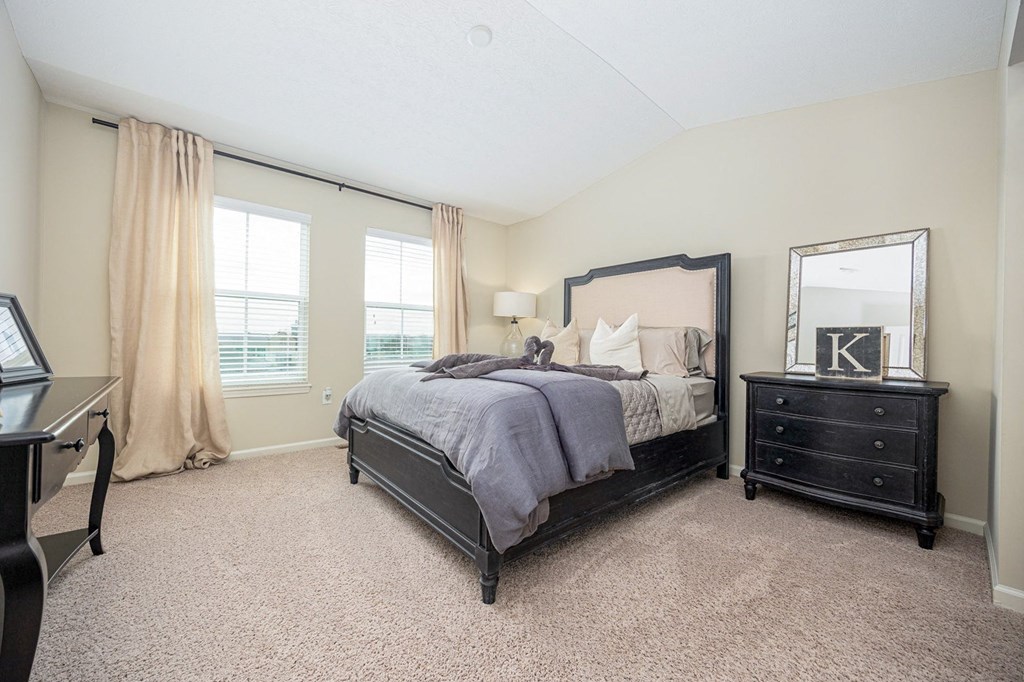 A bedroom with a large bed and a dresser with a mirror.