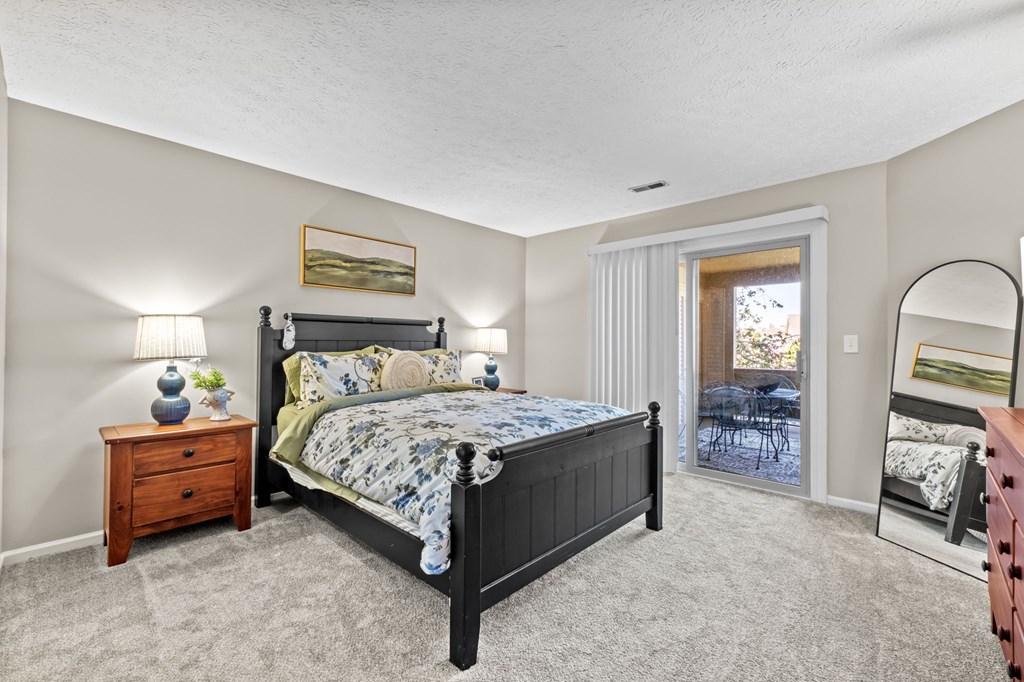 A bedroom with a large bed, a dresser, and a mirror.