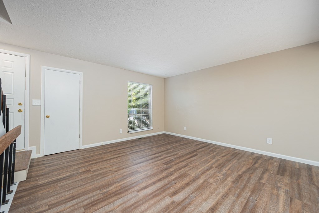 an empty living room with wood flooring and a window