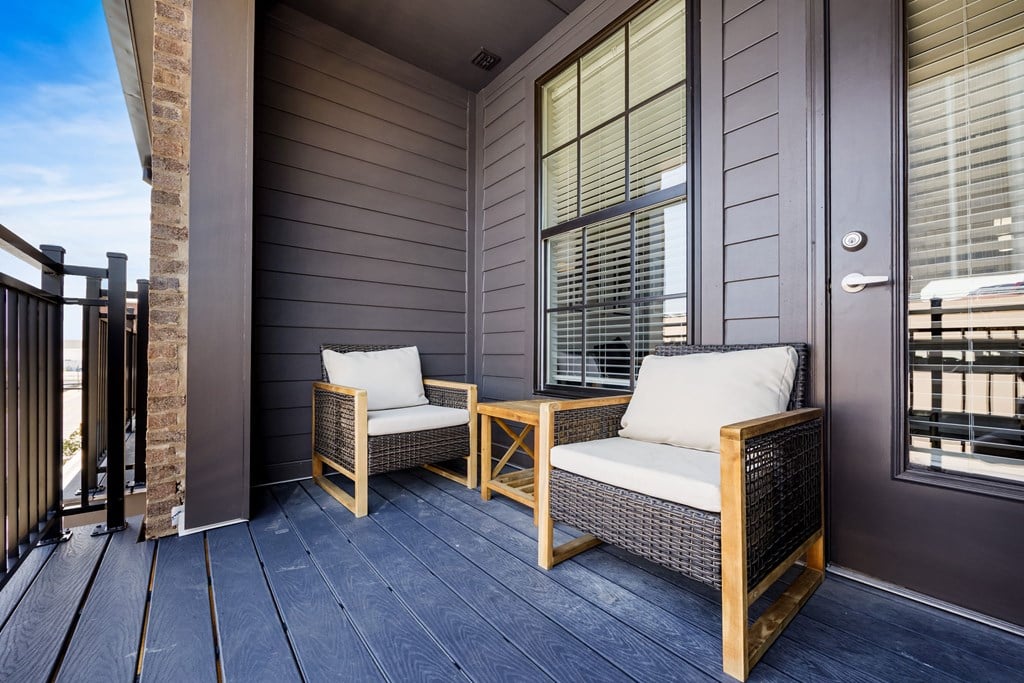 Two chairs and a table on a porch.