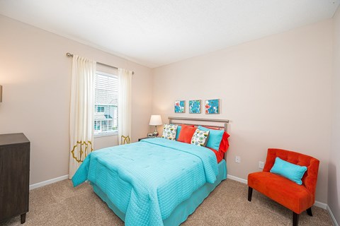 a bedroom with a bed and a chair and a window