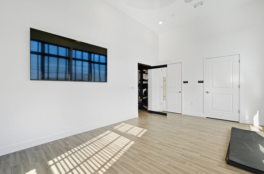 A room with a large window, wooden floors, and white walls.