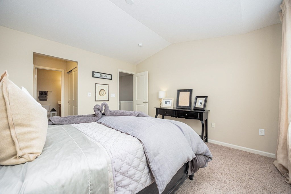 A bedroom with a large bed and a nightstand with a lamp.