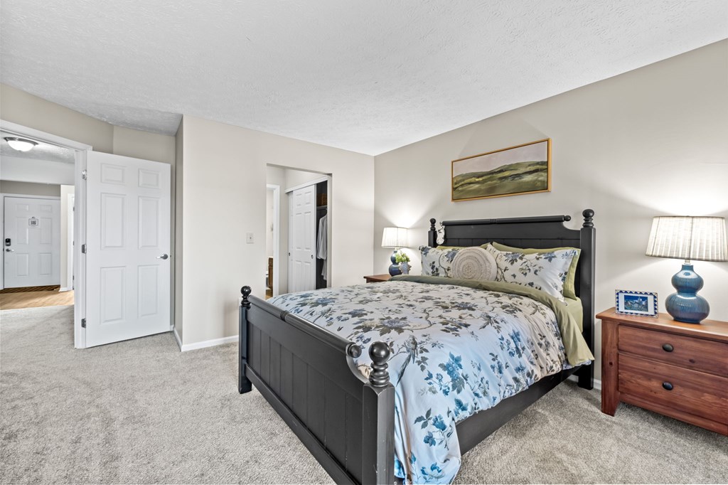 A bedroom with a bed, nightstand, and lamp.