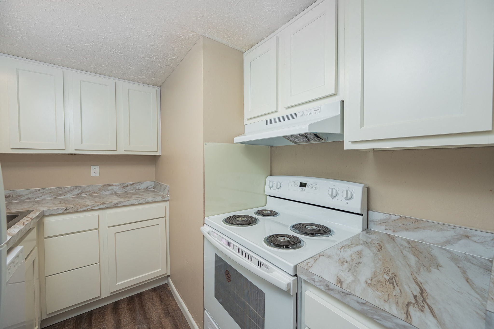 A white stove in a kitchen with white cabinets.