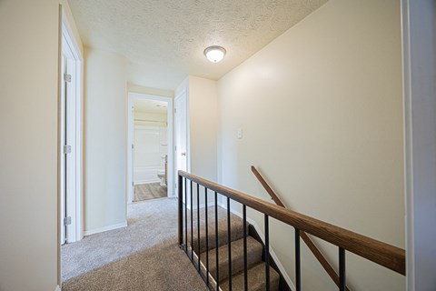 A hallway with a staircase and a light on the ceiling.