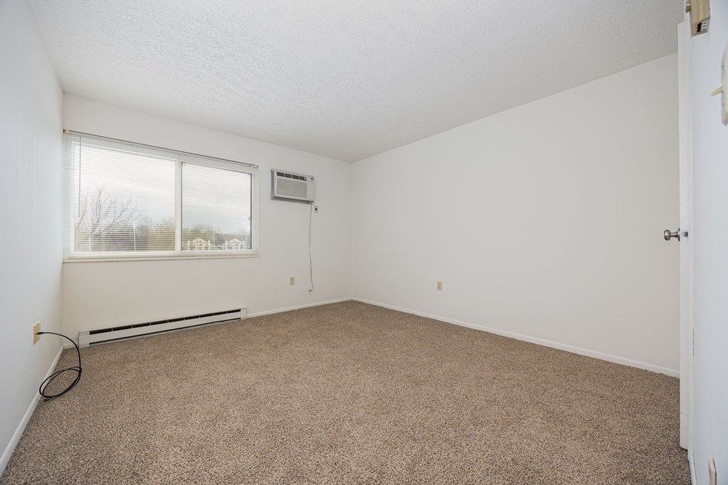A room with a carpeted floor and a window.