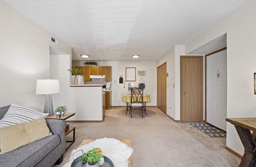 A living room with a grey couch, a coffee table, and a dining table with chairs.