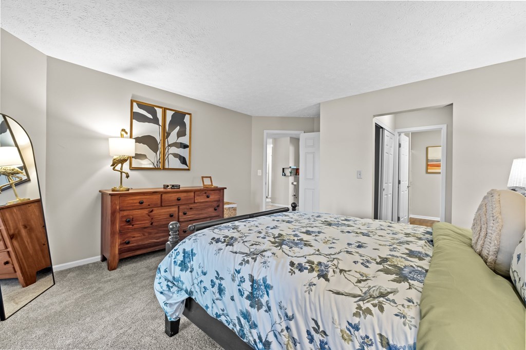 A bedroom with a bed, dresser, mirror, and lamp.