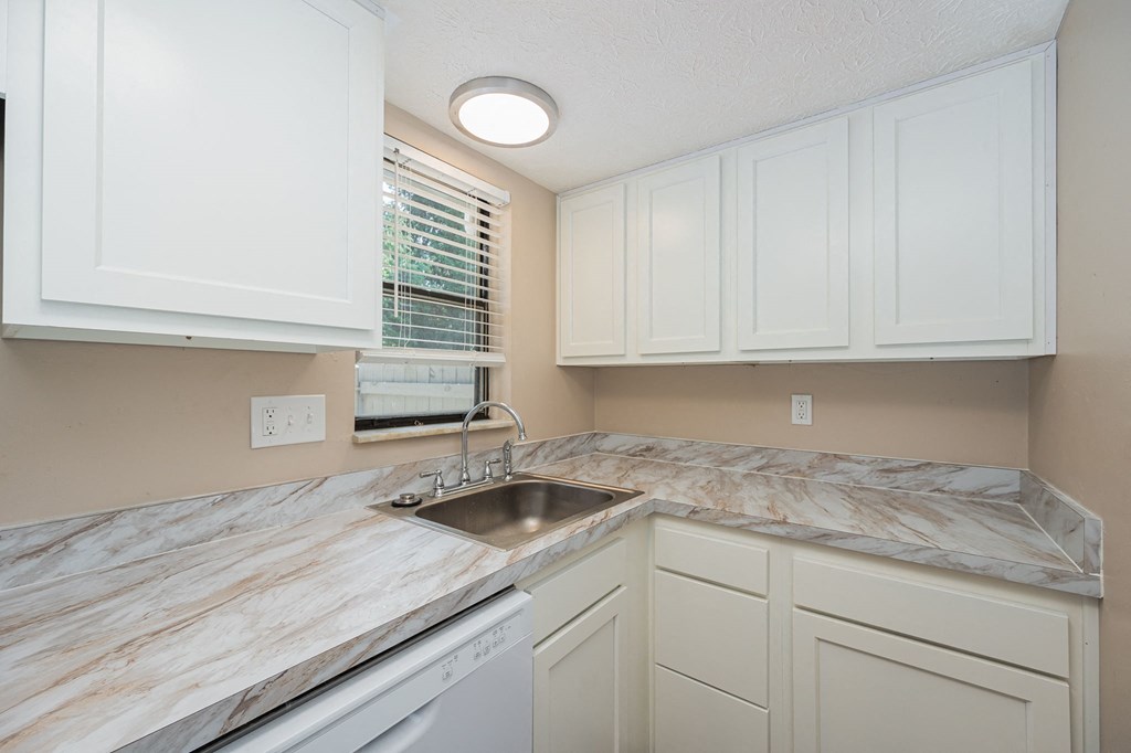 a kitchen with white cabinets and marble counter tops and a sink