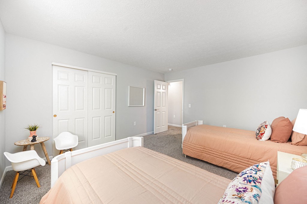 a bedroom with two beds and a chair and a table