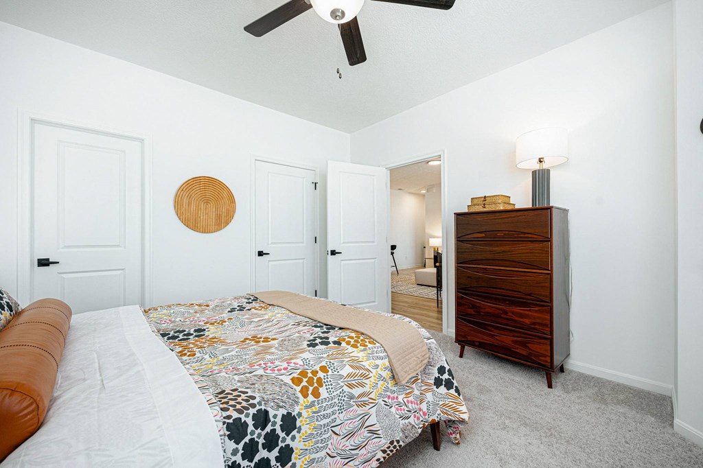 a bedroom with a bed and a dresser and a ceiling fan