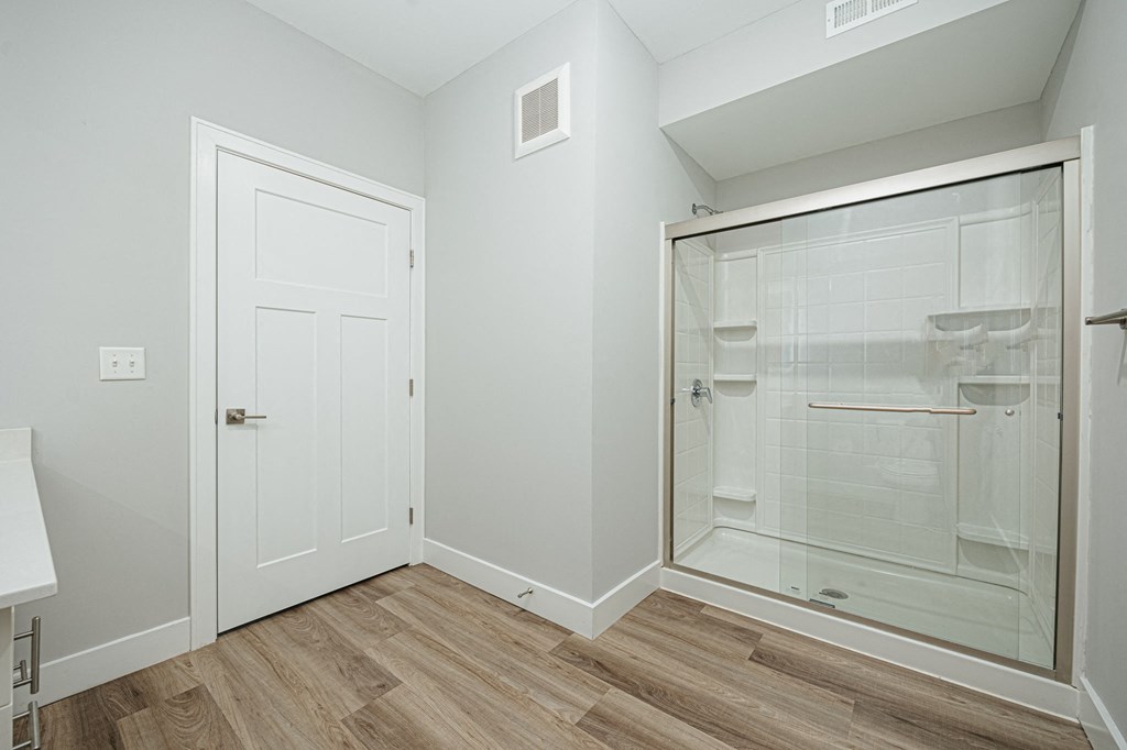a bathroom with a glass shower and a door to the closet