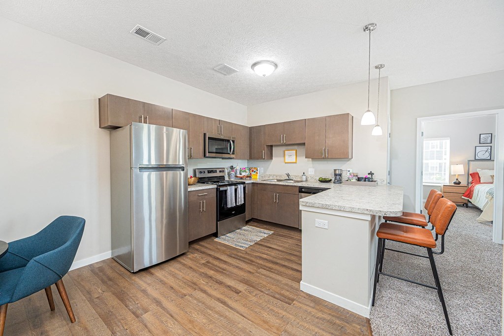 a kitchen and living room with a bar stool and a refrigerator