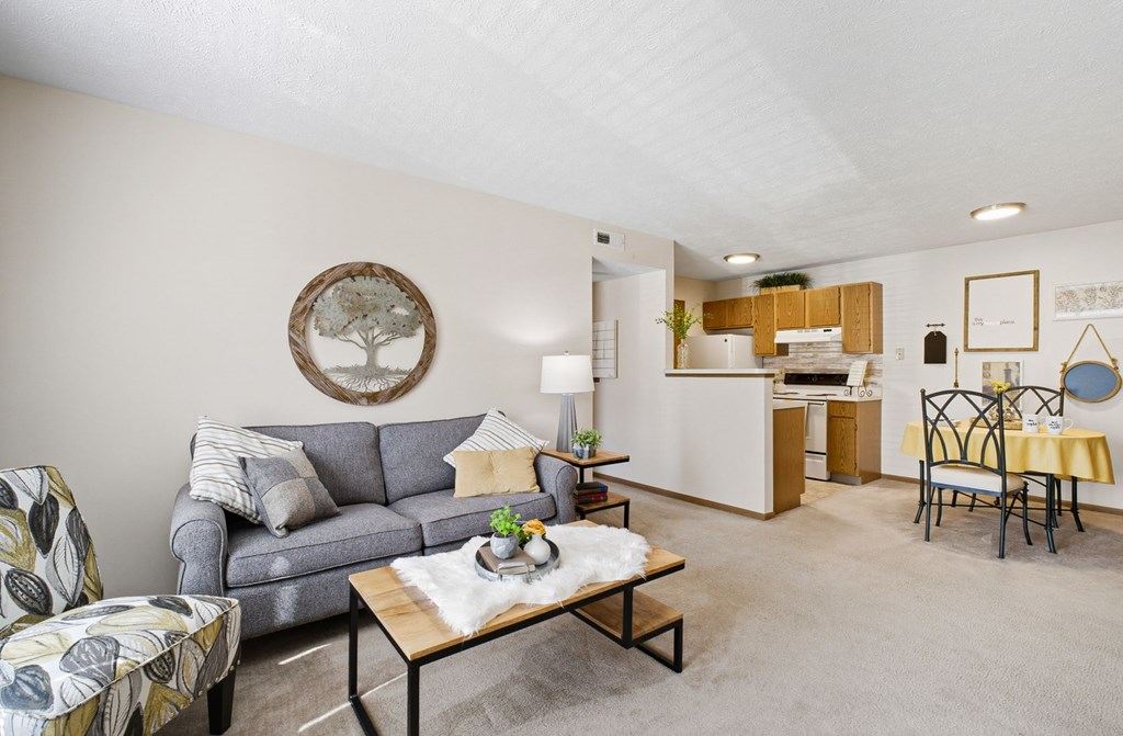 A living room with a grey couch, a coffee table, and a dining area in the background.