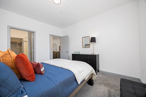 A bedroom with a bed, dresser, mirror and a chair.