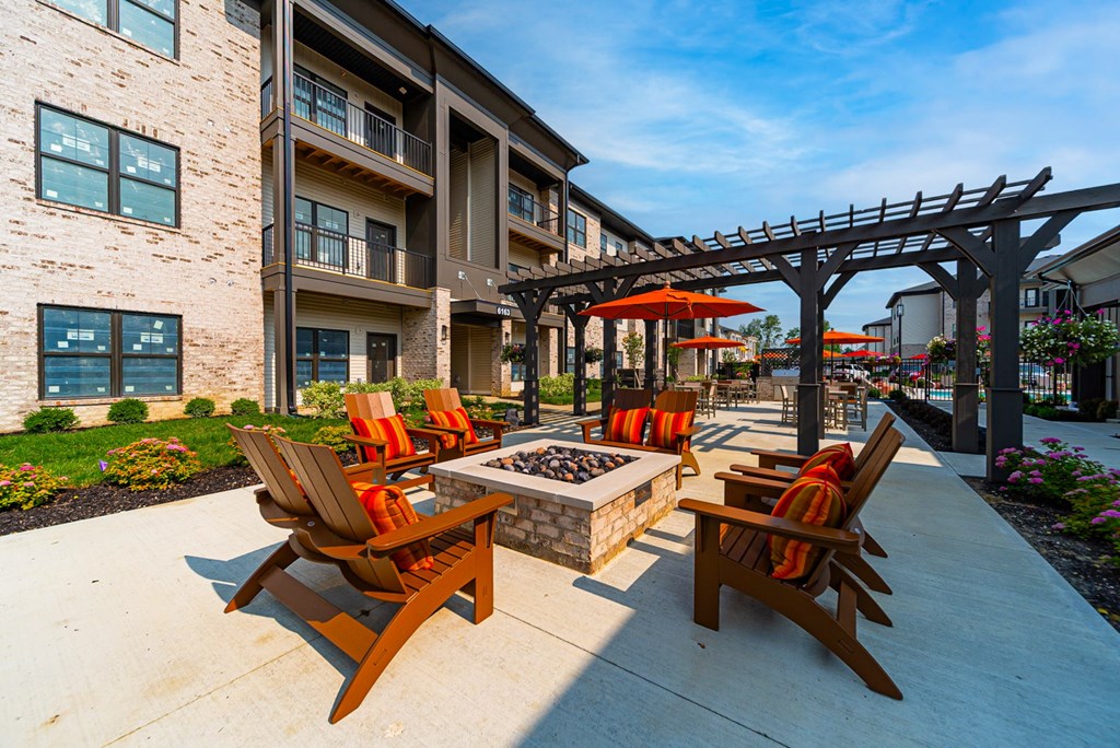 A patio with a fire pit and chairs.