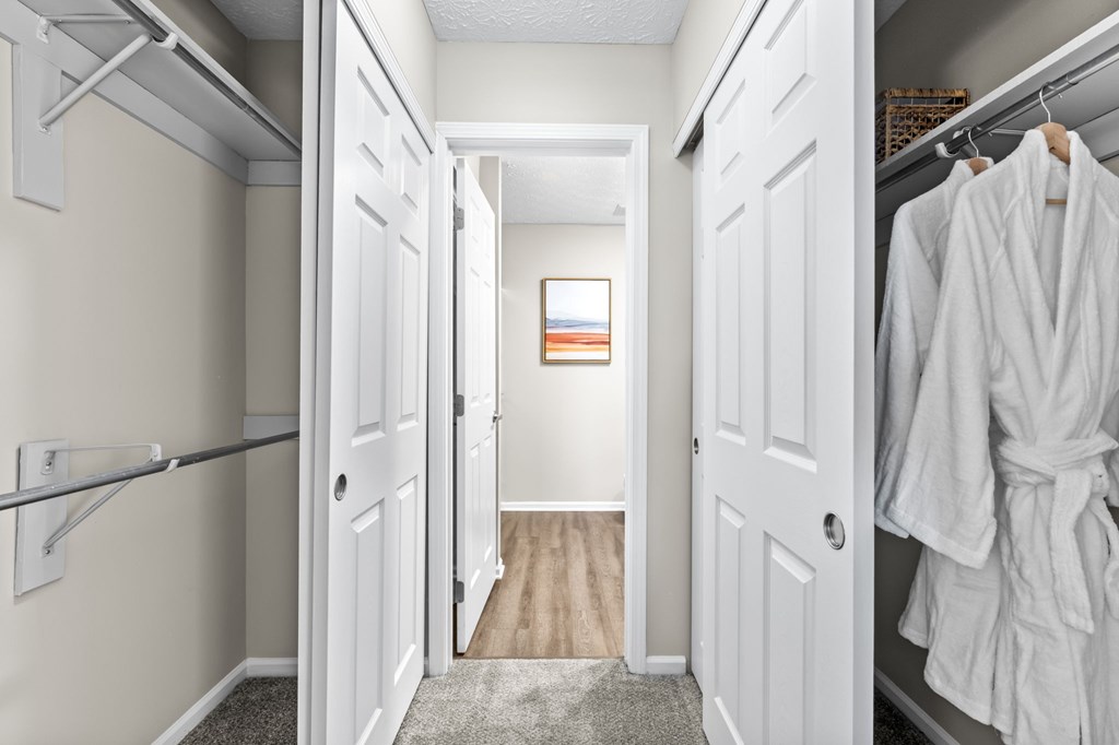 A hallway with white doors and a white robe hanging on the right door.
