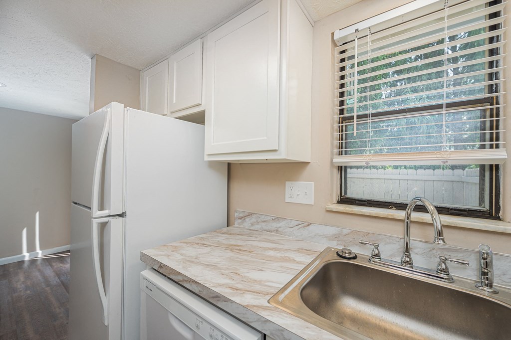a kitchen with a sink and refrigerator and a window