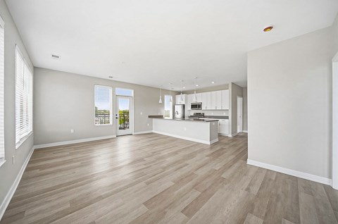A spacious room with wooden flooring and white walls.