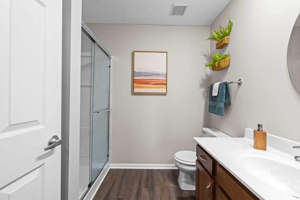 A bathroom with a toilet, sink, and a painting on the wall.