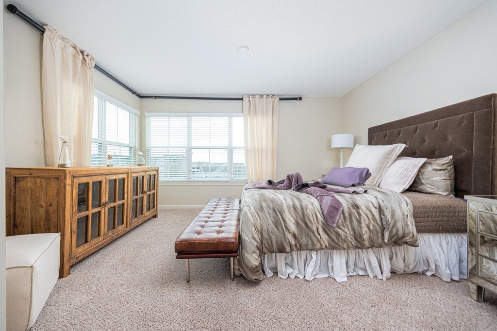 A bedroom with a large bed and a wooden cabinet.