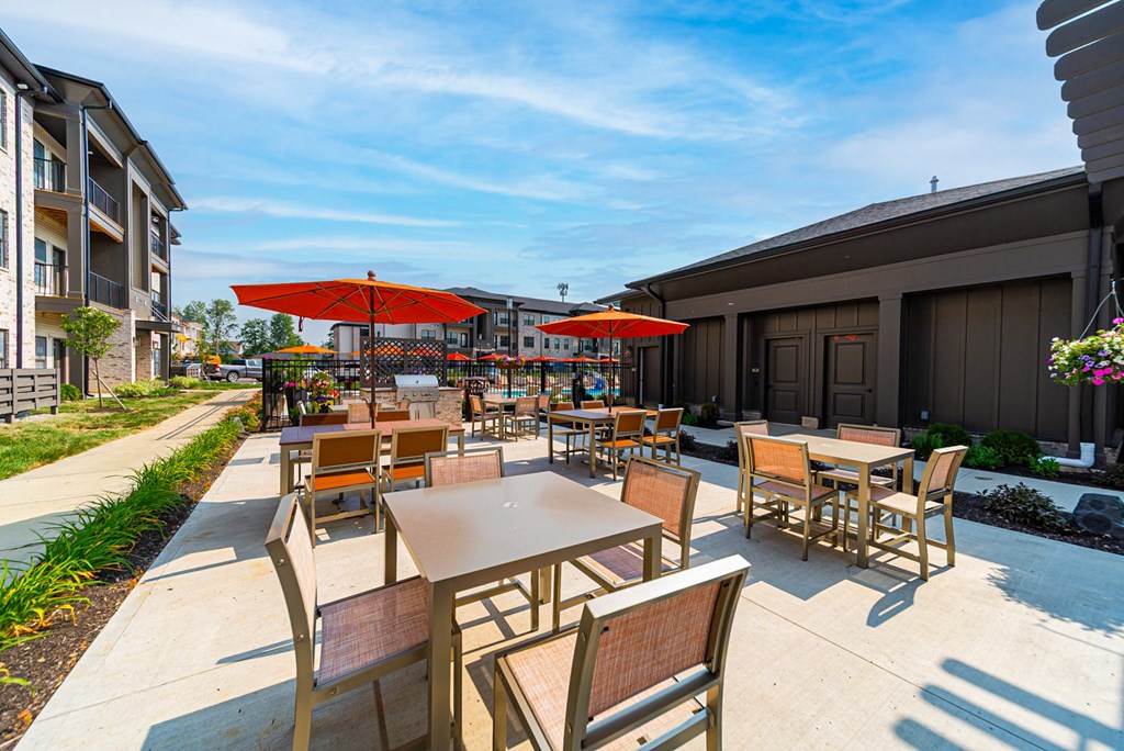 A patio with tables and chairs is surrounded by buildings.