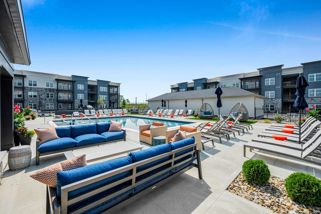 A sunny day at a poolside with blue seating and a statue.