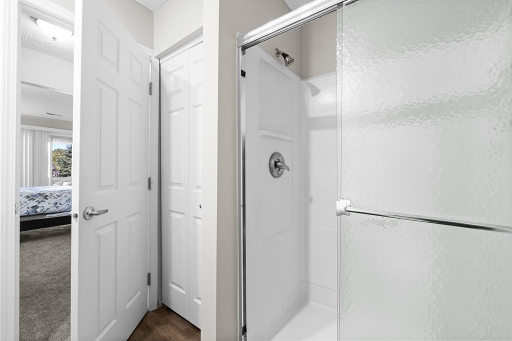 A white bathroom with a glass shower door.