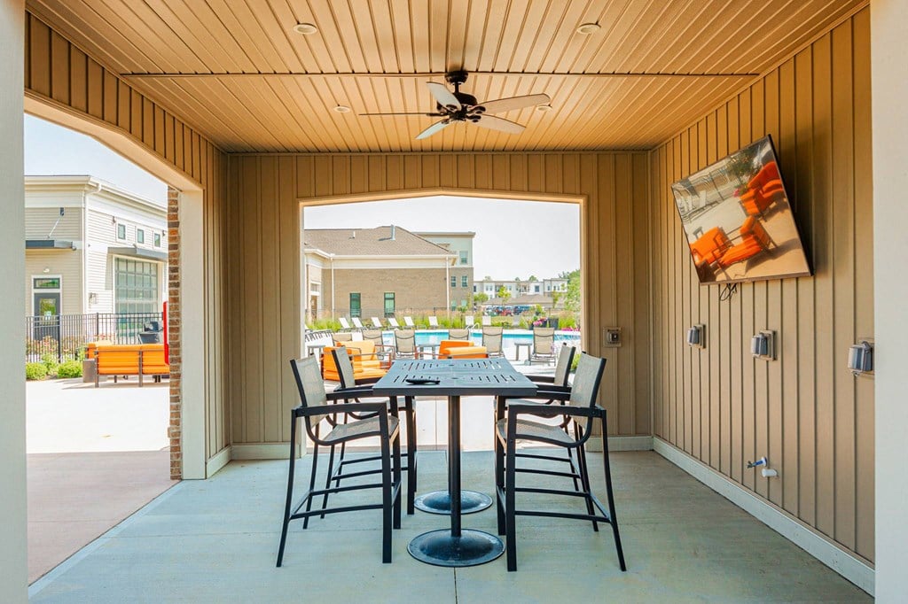 a patio with a table and chairs and a ceiling fan