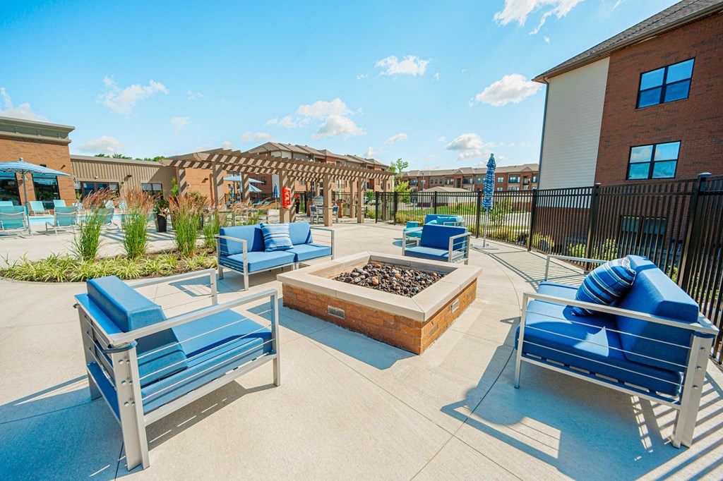a patio with blue chairs and a fire pit