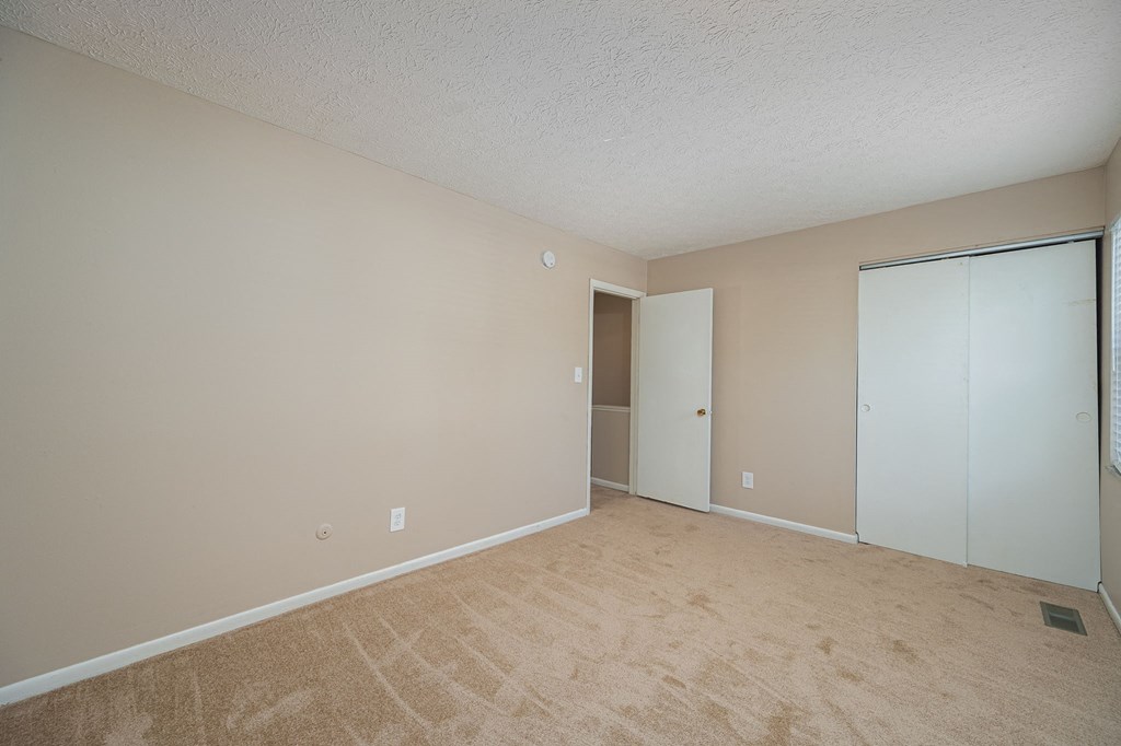 an empty living room with a door to a closet