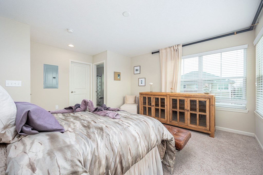 A bedroom with a bed, a window with blinds, and a wooden cabinet.