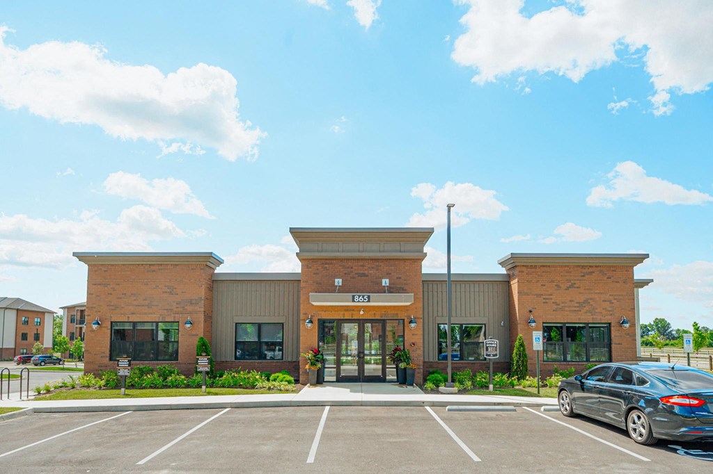the front of a brick building with a car parked in a parking lot