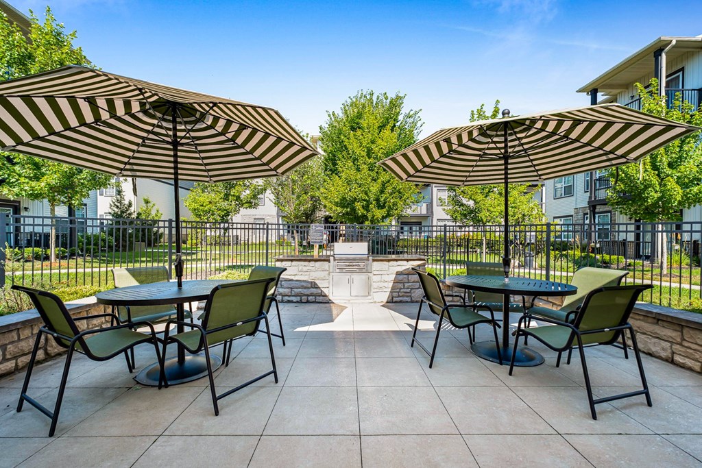 A patio with tables and chairs under striped umbrellas.