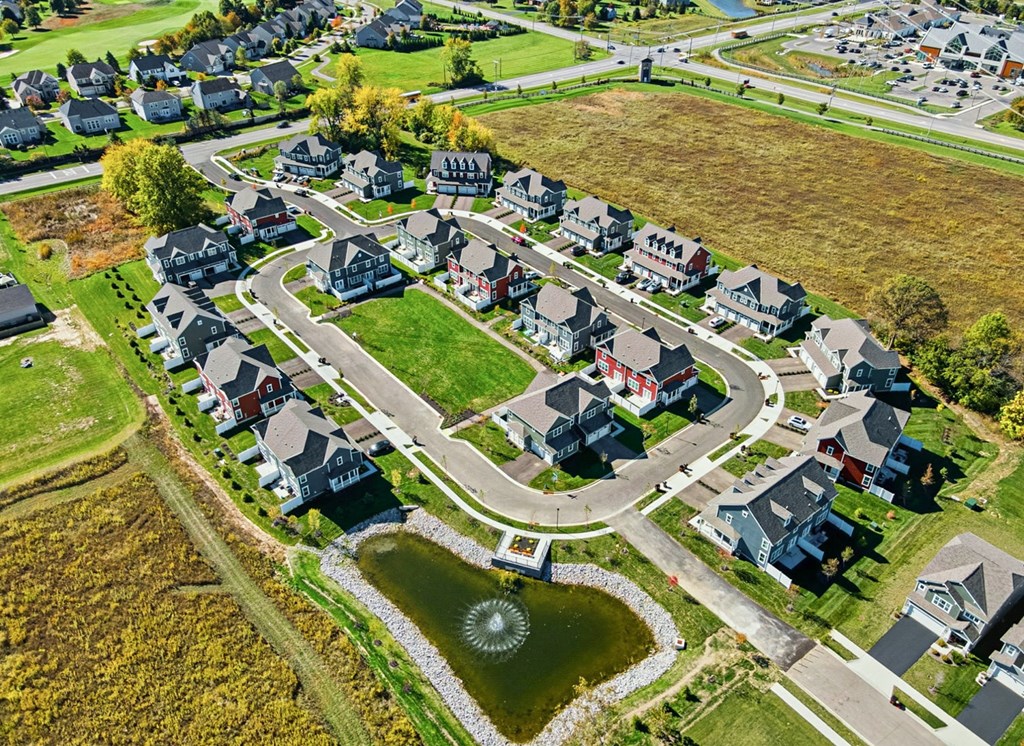 A bird's eye view of a residential neighborhood with houses and a pond.