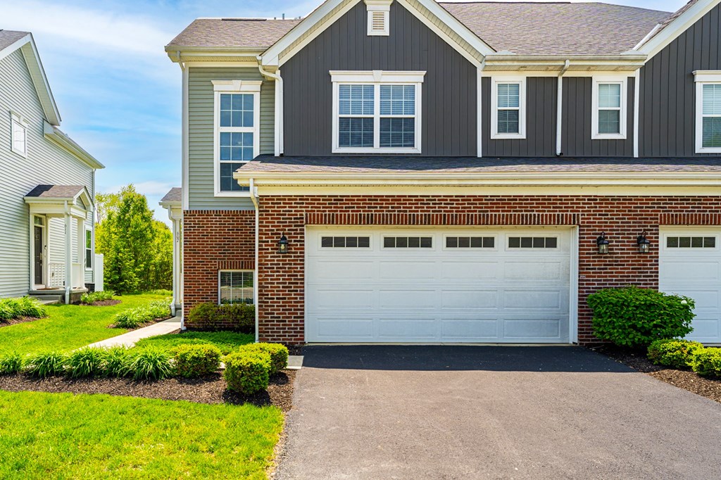 A house with a grey garage door in front of it.