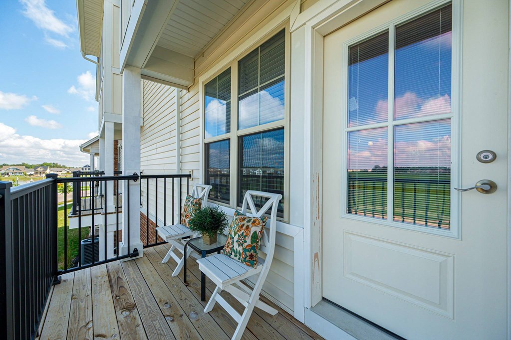 a balcony with chairs and a view of a building with windows